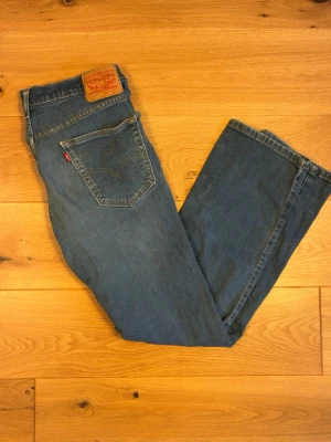 Levi’s 511  W33 L32 - Klassiska Levi’s 511 i medelblå tvätt med snygg naturlig slitning. Slim fit med rak passform nertill, klassisk femficksmodell och äkta läderlapp.  Detaljer:  	•	Modell: Levi’s 511  	•	Storlek: W33 L32 	•	Skick: Använt skick - en mindre fläck på höger ben  	•	Färg: Medelblå tvätt med fin naturlig fading 	•	Äkta läderlapp och röd Levi’s-etikett på bakfickan