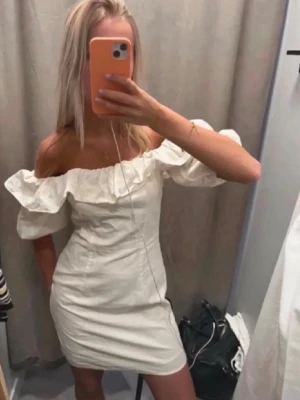 Vit offshoulder klänning - Säljer en vit kortklänning med offshoulder och volangdetalj runt axlarna. Klänningen har puffiga korta ärmar och en figurnära passform. Perfekt för sommarens alla tillfällen💓prislappen kvar 
