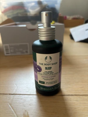 The Body Shop Sleep Pillow Mist - Säljer en Sleep Calming Pillow Mist från The Body Shop med lavendel och vetiver. Flaskan är mörkgrön med sprayfunktion och rymmer 100 ml. Innehåller 100% naturliga eteriska oljor och är vegansk. Perfekt för dig som vill ha en lugnande doft till kudden. Inte helt ny men har använt ett fåtal gånger så flaskan är nästan helt full