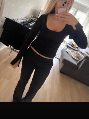 Svart långärmad croppad topp - Snygg svart långärmad topp med croppad passform och fyrkantig ringning. Toppen har en tight siluett och är perfekt för dig som gillar stilrena basplagg med en modern twist.