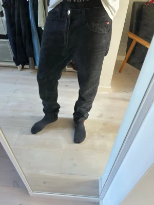 Svarta jeans herr - Säljer ett par svarta jeans med loose fit och låg gren. Jeansen har klassisk femficksdesign, knappgylf och raka ben. Perfekta för en avslappnad och trendig stil. Materialet är denim i bomull.