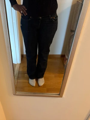 Mörkblå raka jeans - Säljer ett par mörkblå jeans med rak passform och klassisk femficksdesign. Jeansen har normal midja och stängs med knapp och dragkedja. Perfekta för en avslappnad och stilren look.
