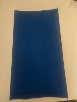 Blå buff - En stilren blå långkjol med rak passform och minimalistisk look. Kjolen är enfärgad och har inga synliga detaljer eller mönster, vilket gör den lätt att matcha med olika toppar. Perfekt för dig som gillar enkel och clean stil.