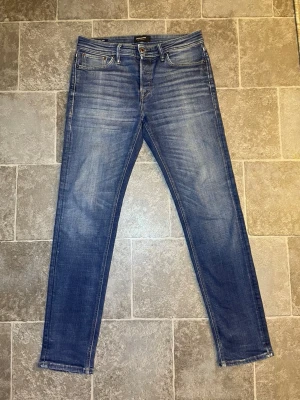 Blå slim fit jeans med slitningar - Snygga blå slim fit jeans med diskreta slitningar och klassisk femficksdesign. Jeansen har normalhög midja och smala ben. Tillverkade i denim med stretch för extra komfort. Perfekta för en avslappnad och trendig look.