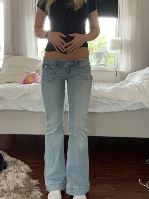 Ljusblå bootcut jeans med låg midja - Säljer ett par ljusblå jeans med bootcut-modell och låg midja. Jeansen är från Nelly och har prislappen kvar, de är i storlek 36-short!
