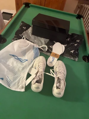 adidas F50 Elite FG Polar Victory – White/Blue – EU 40 2/3 – Oanvända - adidas F50 Elite FG fotbollsskor i vit/blå färg.  Köptes för ungefär ett år sedan direkt från adidas hemsida men har aldrig kommit till användning. Skorna är därför helt oanvända och i mycket fint skick.  • Modell: adidas F50 Elite FG • Produktkod: IE1204 • Storlek: EU 40 2/3 • Originalkartong medföljer • adidas F50-skobag medföljer • Extra innersulor medföljer • Tags finns kvar  Pris kan diskuteras. Skicka gärna ett meddelande om du vill ha fler bilder eller har några frågor.