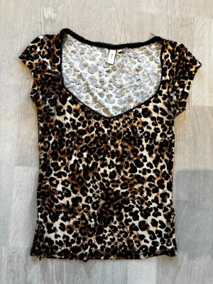 Leopardmönstrad topp med v-ringning - Snygg topp med leopardmönster och v-ringad hals. Kortärmad modell i stretchigt material som sitter tight. Perfekt för dig som vill sticka ut med ett djurmönster.