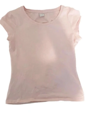 Ljusrosa basic t-shirt i bomull - En enkel och stilren ljusrosa t-shirt med rund hals och korta ärmar. Tillverkad i mjuk bomull som känns skön mot huden. Perfekt att matcha med jeans eller kjol för en avslappnad look.