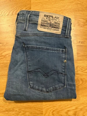 Blå jeans från Replay Anbass  - Snygga blå jeans från Replay med klassisk femficksmodell och ljus färg. Jeansen har modellen anbass och detaljerade sömmar på bakfickan. Perfekta för en avslappnad och trendig stil från de kända märket Replay 
