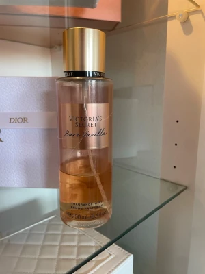 Victoria's Secret Bare Vanilla mist - Fräsch doftmist från Victoria's Secret i doften Bare Vanilla. Flaskan är genomskinlig med guldigt lock och etikett, och rymmer 250 ml. Doften har inslag av vispad vanilj och mjuk kashmir för en varm och söt känsla.