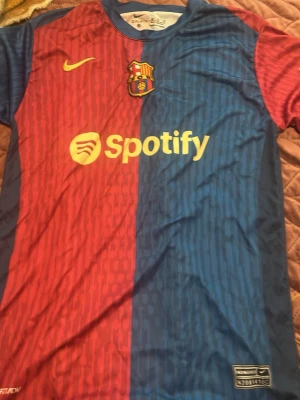 Barcelona matchtröja Gavi nr 6 - Snygg Barcelona matchtröja i rött och blått med gula detaljer. Tröjan har klubbmärke, Nike-logga och Spotify som sponsor framtill. På ryggen står det Gavi och nummer 6 i gult. Tillverkad i ett lätt och ventilerande material, perfekt för fotbollsträning eller match.