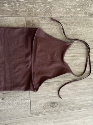 Brun halterneck linnetopp Bik Bok - Säljer en brun halterneck linnetopp från Bik Bok i storlek XS. Toppen har tunna knytband i nacken och är tillverkad i mjuk bomull. Perfekt att styla med jeans eller kjol för en trendig look.