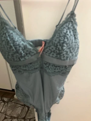 Grå spetsbody från Hunkemöller - Supersnygg grå body från Hunkemöller med tunna axelband och vackra spetsdetaljer upptill och nertill. Materialet är en kombination av mjuk spets och slät tyg, vilket ger en lyxig känsla. Perfekt för att känna sig extra fin.