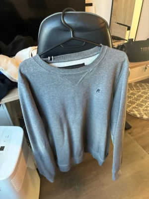 Grå sweatshirt från Replay - Snygg grå sweatshirt från Replay med rund halsringning och diskret logga på bröstet. Tröjan har långa ärmar och mjukt material på insidan, perfekt för en avslappnad stil. Klassisk passform och enkel design som funkar till det mesta.