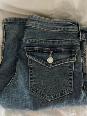 Blå raka jeans med ficklock - Säljer ett par klassiska blå jeans med bootcut och ficklock bak med knappdetalj. 