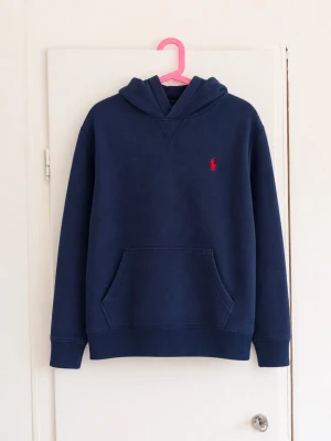 Polo Ralph Lauren hoodie i klassiskt mörkblått 💙 - Stilren och tidlös hoodie med röd broderad Polo-logga på bröstet, känguruficka framtill och mjuk insida. Enkel att matcha och perfekt till vardags.  • Märke: Polo Ralph Lauren • Storlek: M (10–12 år), ca 150 • Färg: Mörkblå/navy • Hoodie utan dragkedja • Känguruficka framtill • Röd broderad Polo-logga • Ribbad mudd vid ärmar och nederkant  Fint begagnat skick utan defekter!😁 Etikett och QR-märkning finns kvar!