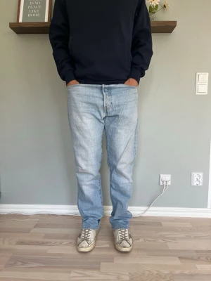 Levi’s 501 Vintage Jeans W32 L32 Ljustvättad Denim - Levi’s 501 i ljus, urtvättad denim med fint naturligt slitage genom hela plagget. Rak passform, knappgylf, klassisk femficksmodell med skinnlapp bak.  Skick: bra skick Material: denim (100% bomull) Midja: W32 Innerbenslängd: L32 Modell: 175 cm / 65 kg