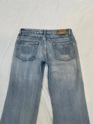 Lågmidjade bootcut jeans med detaljer - Kronor på fickorna bak och fram😍mått finns på bilderna. Obs liten fläck fram på låret kolla bilderna noga! 4% elastan alltså ganska stretchiga. Står W31 på lappen vilket motsvarar L/XL enligt Google