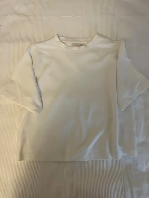 Vit basic t-shirt från 157 - En enkel och stilren vit t-shirt från 157 med rund hals och korta ärmar. Tillverkad i mjuk bomull och har en normal passform. Perfekt att matcha med jeans eller shorts för en clean look. Använd väldigt lite.