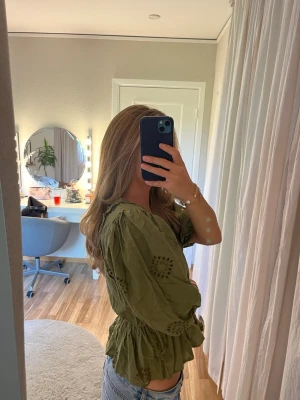 Blus  - Grön blus med fina detaljer och volang vid magen