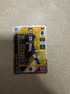 Match Attax samlarkort Lionel Messi PSG - Samlarkort från Match Attax med Lionel Messi i Paris Saint-Germain. Kortet har guldfärgade och silvriga detaljer, visar Messi i PSG:s hemmaställ och har texten 'MATCHWINNER'. Kortet är rektangulärt och gjort av glansig kartong, perfekt för fotbollsfans och samlare. 