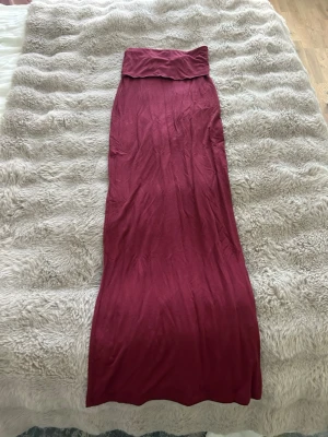 Vinröd långkjol från Gina Tricot - Säljer en vinröd långkjol från Gina Tricot i mjukt och stretchigt material. Kjolen har en enkel och stilren design med hög midja och rak passform. Perfekt att styla med en crop top eller stickad tröja.