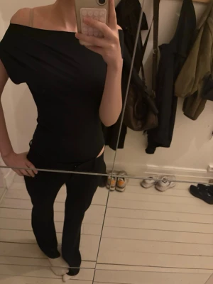 Svart offshoulder topp - Snygg svart offshoulder topp med tight passform. Toppen är ärmlös och har en stilren, enkel design som passar perfekt till många olika outfits. Materialet känns mjukt och stretchigt, vilket gör den bekväm att bära.