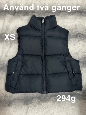 Svart väst XS - Svart väst modell med hög krage och dragkedja framtill. Västen har två fickor och en clean, stilren look. Perfekt att bära över hoodie eller tröja för extra värme.🌸 Använd två gånger. Storlek XS 