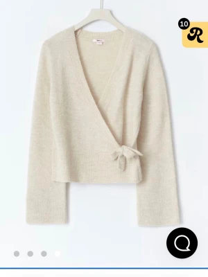 Beige omlottkofta  - Mysig beige omlottkofta med rosett i sidan och djup v-ringning från Gina. Finns flera bilder att visa det är bara att säga till isf. 