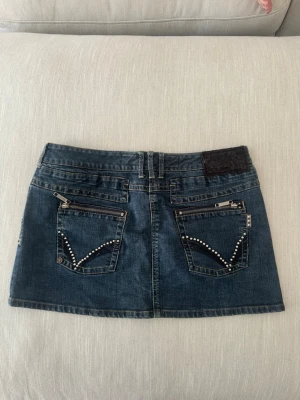 Mörkblå jeanskjol med nitar och dragkedjor - Snygg mörkblå jeanskjol som är använd ett par fåtal gånger. Den är normal i storleken och stretchig💕