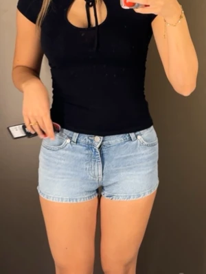 Ljusblå denimshorts med fickor - Säljer ett par ljusblå denimshorts i klassisk femficksmodell. Shortsen har normal passform, midwaist och snygga bakfickor med knappdetalj. Perfekta till sommaren och lätta att matcha med olika toppar.