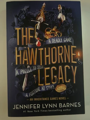 The Hawthorne Legacy - En spännande engelskspråkig roman av Jennifer Lynn Barnes. Boken har ett mörkblått omslag med guldtext och detaljer som svärd, krona och smycken. Den handlar om mysterier, gåtor och arv i en värld av rikedom och svek. Perfekt för dig som gillar mysterier och ungdomsböcker.