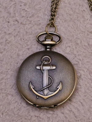 Fickur - klocka - Ankare - Bilderna visar en antik fickur med ankare på framsidan och blommigt mönster på baksidan.