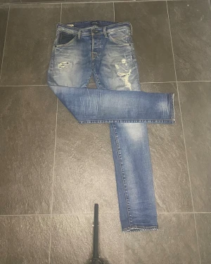 Jack & Jones slim fit Glenn blå jeans - Slim fit jeans från Glenn i klassisk blå tvätt med slitningar och distressed detaljer på framsidan. Modellen har fem fickor, dragkedja och knappstängning. Jeansen är tillverkade i jeansmaterial och har en smal passform som sitter snyggt längs benen. Hör av dig vid frågor eller prisförslag!🤝