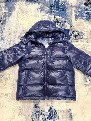 Ralph lauren vinterjacka - Säljer denna asfeta blå glansiga Ralph Lauren jackan i storlek M. Jackan är aldrig använd med tags kvar. Köpt på plick, inget kvitto finns! Han på bild är 185cm, 75kg. Hör av er vid funderingar!