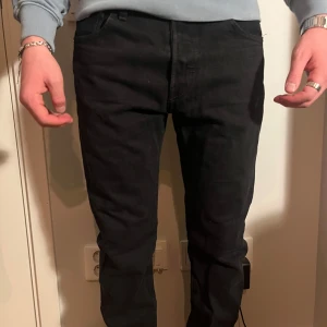 Svarta jeans från Levi's - Säljer ett par svarta Levi's jeans i mycket bra skick. De har en klassisk design med fem fickor och en knappgylf. Perfekta för både vardag och fest! Passar till allt och är superbekväma. Passar dig som är ca 175 och väger 60kg