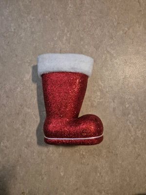 Julstövel - En riktigt festlig julstövel i rött glitter med fluffig vit kant upptill. Stöveln har en rund tå och en söt liten smiley framtill. Perfekt som dekoration eller för att fylla med småsaker under julen.