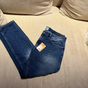 Dondup jeans  - Snygga blå jeans från Dondup, tillverkade i Italien. Klassisk femficksmodell med ljus tvätt och subtila slitningar. Jeansens passform är rak och de har en brun läderpatch med logga baktill. Perfekta för dig som gillar stilrena och tidlösa jeans. Jeansen är köpta från Sellpy så kan inte garantera att den är helt nya men som sagt är den i väldigt bra sick utan defekter.
