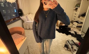 Mörkblå stickad tröja  -  mörkblå stickad tröja med loose fit och långa ärmar. Tröjan har en enkel, rund halsringning och är perfekt för dig som gillar en chill och avslappnad stil. 