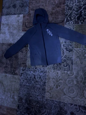 Trapstar London Shooters vindjacka - Säljer en Trapstar London Shooters vindjacka med huva och snörning. Jackan har svart dragkedja, vita tryck på bröstet och ryggen, jackan kommer med en liten ficka med dragkedja vid armarna. Top kvalité🤩(priset kan diskuteras)