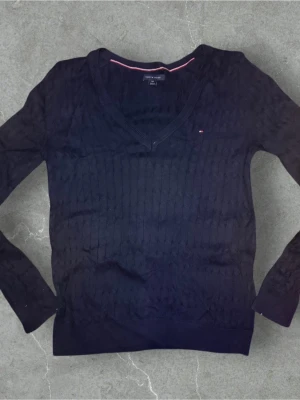 Marinblå stickad tröja Tommy Hilfiger - Snygg marinblå stickad tröja från Tommy Hilfiger med v-ringad hals och diskret logga på bröstet. Perfekt om man vill ha något avslappnande! Skick 8-10🌟 Den är i storlek S🤩 Skriv gärna om ni har funderingar🤗
