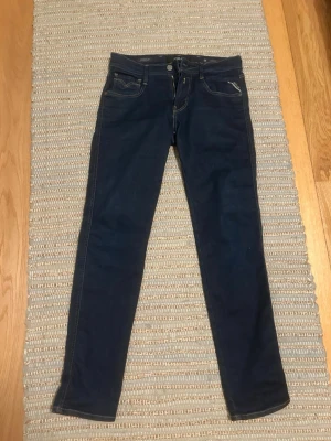 Replay Hyperflex mörkblå jeans - Snygga Replay Hyperflex jeans i mörkblå tvätt. Jeansen är använda 2-3 gånger och inga täcken på slitage. Modellen har raka ben och normal passform, med läderpatch bak i midjan och coola detaljer på fickorna. Perfekta för dig som gillar stilrena och bekväma. Tveka inte att höra av er om frågor!  Kan gå ner i pris vid snabb affär. 