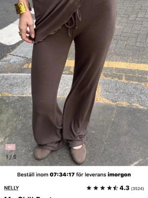 Low waist byxor nelly - Snygga bruna mjukisbyxor från Nelly med breda ben och skön loose passform. Byxorna har snörning i midjan och är tillverkade i mjukt material som känns chill och bekvämt. Perfekta för en avslappnad look och passar till sneakers eller loafers. 