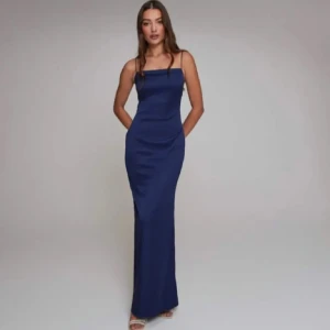 Mörkblå långklänning med öppen rygg - Säljer en elegant mörkblå långklänning med smala axelband och en fantastisk öppen rygg. Perfekt för festliga tillfällen! Klänningen har en tight passform som framhäver figuren.