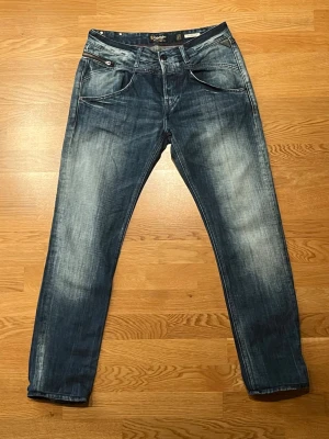 Replay jeans 27/32 - Snygga blå jeans från Replay i straight fit med klassisk femficksdesign och coola slitningar. Jeansen har normal passform och är tillverkade i slitstarkt denim. Perfekt för dig som gillar en tidlös look med lite edge.