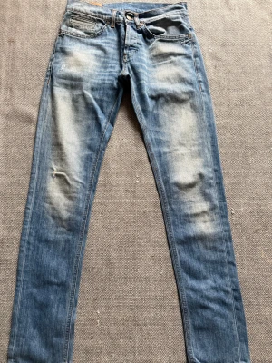 Ljusblå Dondup jeans  - Säljer ett par snygga Replay Anbass jeans i blå tvätt med slitningar och skinny passform. Jeansen har klassiska fem fickor, ljusa detaljer och Replay-logga på bakfickan. Perfekt för dig som gillar en smal siluett och coola slitningar. Dm för frågor!🙌