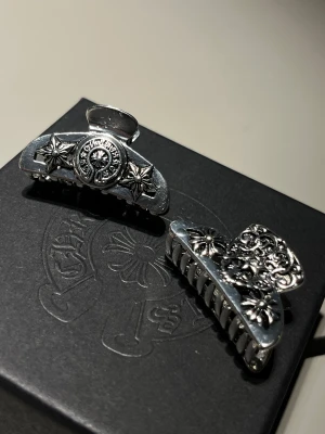Chrome Hearts silver klämma - Säljer två unika silverfärgade Chrome Hearts klämmor. Klämmorna är gjorda i metall och är i mycket bra kvalitet. All förpackning ingår såklart, och om mi vill ha fler bilder eller allmäna frågor är det bara att höra av sig :)