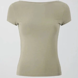 Grön topp med öppen rygg - Stilren topp med korta ärmar och en djup, öppen rygg. Toppen har en tight passform. Perfekt för dig som vill ha en enkel men snygg look.