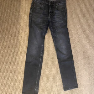 Svarta skinny jeans med slitning - Snygga svarta skinny jeans med lätt tvättad look och slitning vid grenen. Klassisk femficksmodell med dragkedja och knapp framtill. Jeansen har smal passform och raka bakfickor med dekorativ söm. Sönder (se bild 2) däremot lagat.