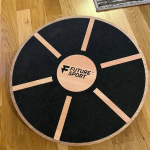 Future Sport Balansbräda - Balansbräda från Future Sport i trä med halkskyddad yta. Perfekt för träning av balans, koordination och styrka. Brädan är i mycket gott skick utan synligt slitage eller defekter. Stabil konstruktion med robust plastfot undertill för säker användning.